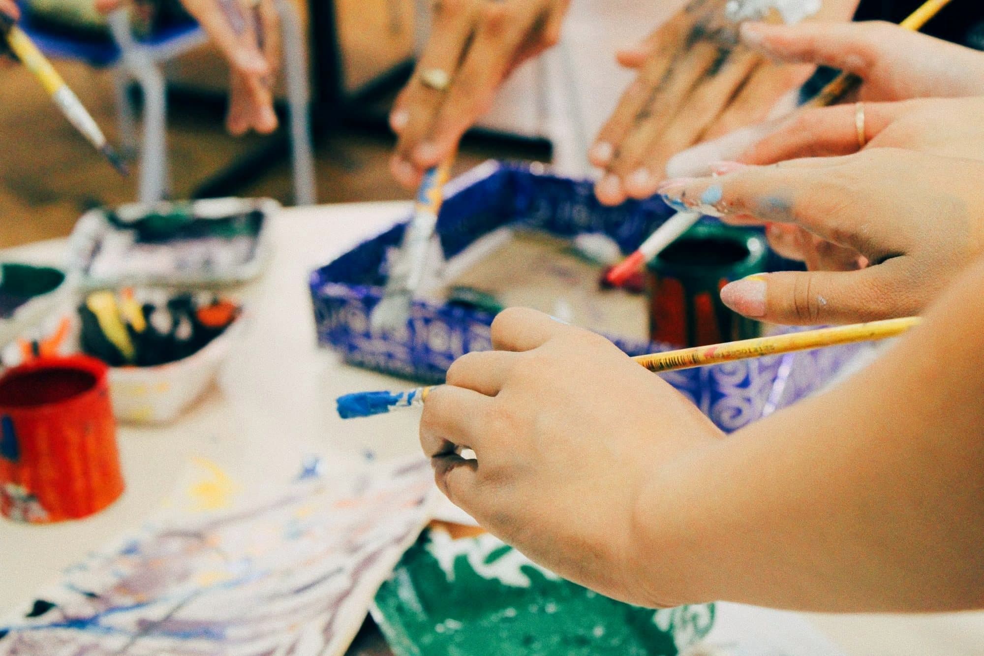 Young people's hands painting together around a table