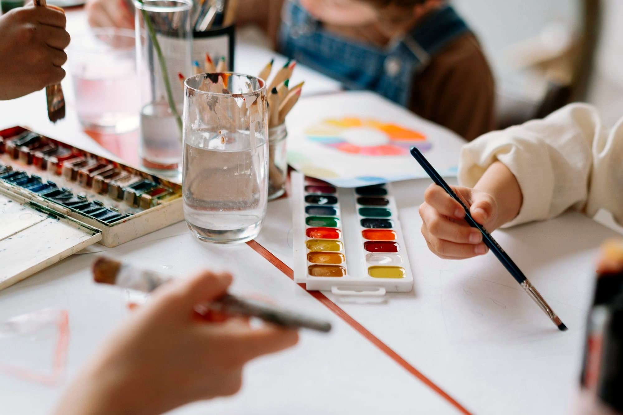 Children's hands painting with watercolours at a table